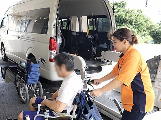車椅子移動の場面 スタッフイメージ スタッフが車椅子を押し、安全かつ丁寧に移動をサポートしています。安心して働ける環境です。