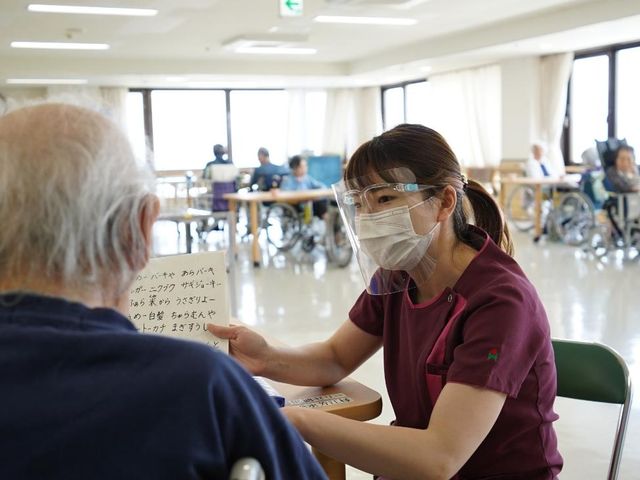 笑顔のスタッフと交流する室内 リビング 広々とした明るい空間で、利用者様同士やスタッフとの和やかな交流が見られます。