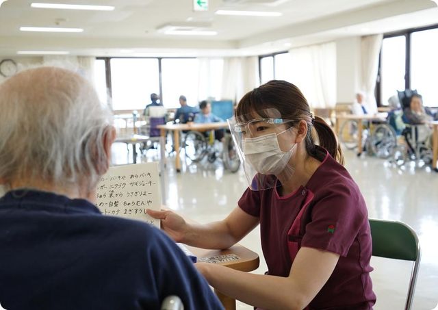 笑顔のスタッフと交流する室内 リビング 広々とした明るい空間で、利用者様同士やスタッフとの和やかな交流が見られます。