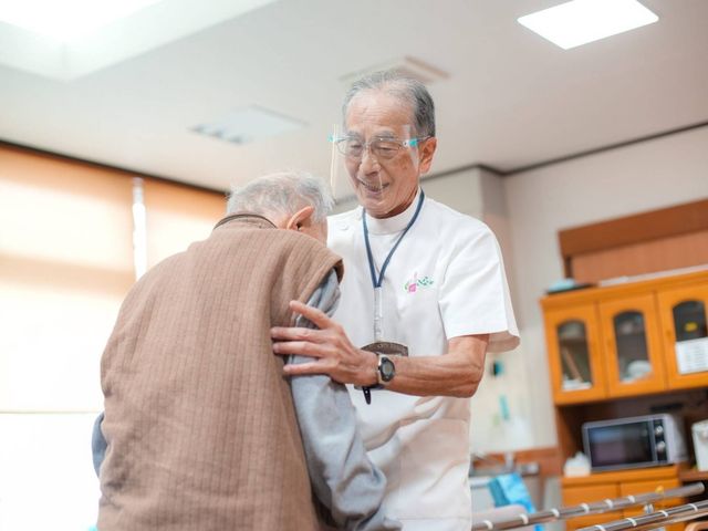 人がサポートされる室内 内観 温かみのある空間で、スタッフが利用者を親身にサポートしています。自然光が差し込む明るい室内です。