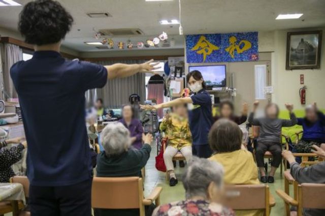 人々の体操風景 多目的室 体操を行う集まりで、皆が和やかに参加しています。アクティビティを通して交流が深まります。