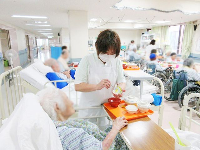 介護職の様子の場面 リビング 広々とした空間で介護職員が利用者のケアを行っています。快適な環境で働けます。