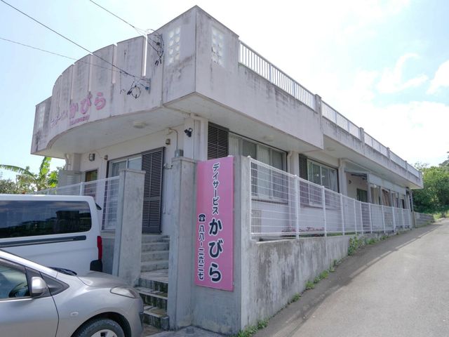 看板と建物の外観 外観 施設の外観には、駐車場と広い入口が備えられています。車椅子の方でもアクセスしやすいです。