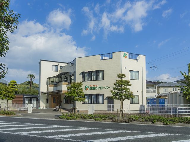 施設の外観 外観 青空の下に建つ明るい建物で、1階には入口が見えます。周囲には木々があり、落ち着いた雰囲気です。