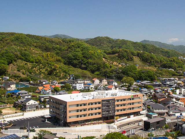 山あいの施設外観 外観   緑の山々に囲まれた立地で、周辺の住宅街にもなじむ落ち着いた外観です。働く環境の雰囲気をイメージしやすい景色になっています。