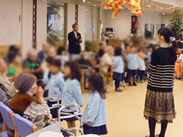 交流する人々と椅子の廊下 廊下 子供たちと高齢者が集い、心温まる交流の様子が見られる広々とした空間です。