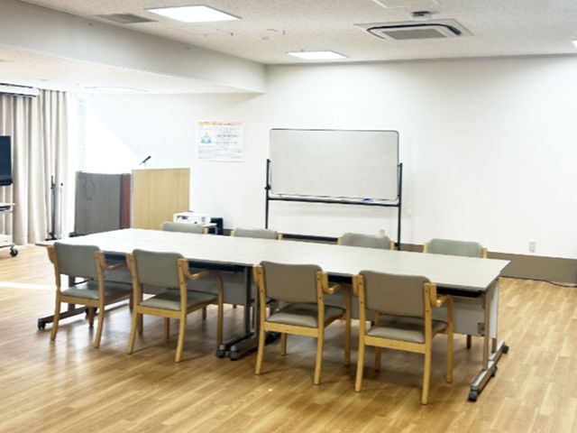 研修用テーブルの部屋 多目的室 広々とした多目的室には大きなテーブルと椅子があり、研修や会議に適しています。白板も完備されており、様々な用途に対応可能です。