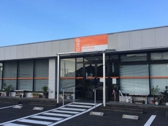 看板のある建物外観 外観 広々とした駐車スペースが整えられている建物の前です。訪れる方々に親しみやすい印象を与えます。
