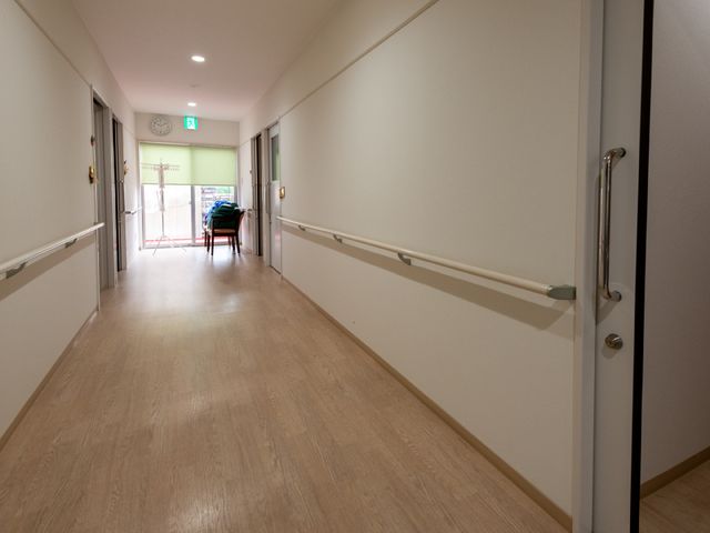 赤い椅子のある廊下 廊下 ゆったりとした廊下には手すりが設置されており、安全に配慮された設計です。明るくゆったりとした通路で、快適な勤務が期待できます。