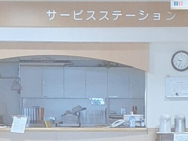 サービスステーションの窓口 フロント   サービスステーションの窓口が見える落ち着いた空間です。時計や掲示物もあり、案内や見守りの場面が想像しやすいです。