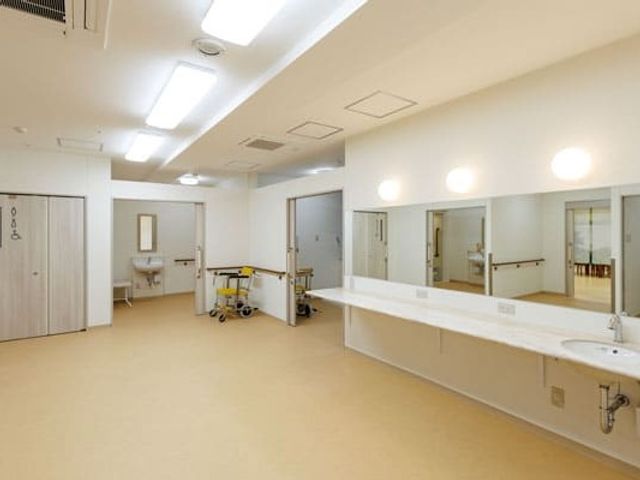 明るい洗面台付き廊下 廊下   幅の広い廊下に洗面台が並び、明るい照明で清潔感があります。手すりもあり、移動しやすそうです。