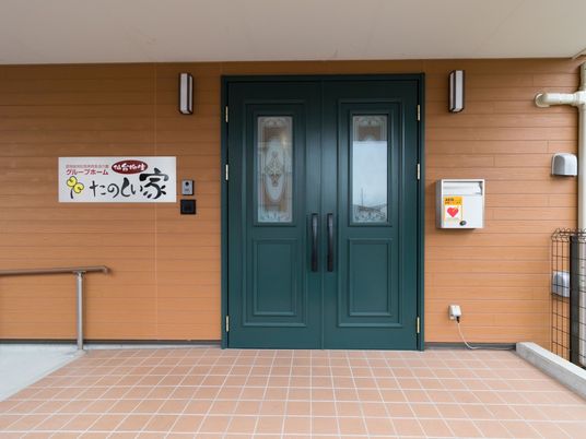 緑の扉と看板のエントランス