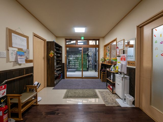 明るい玄関の廊下 玄関 気配りが行き届いたエントランスには、情報掲示物が整然と配され、訪れる方々を暖かく迎えています。靴を揃えるスペースや手指消毒設備も整い、清潔感が漂います。
