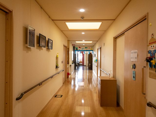 明るい廊下とアート作品 廊下 清潔で温もりのある廊下が、訪れる方々を優しく迎え入れます。壁に飾られた絵画が、日々の生活に彩りを添えています。
