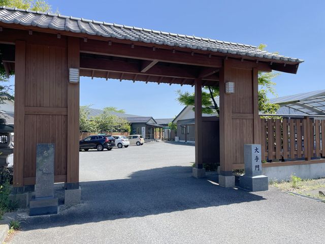 穏やかなエントランス風景 エントランス 木造の門をくぐると、静かな広場が広がる落ち着いた入口です。お車でのアクセスも便利な様子が伺えます。