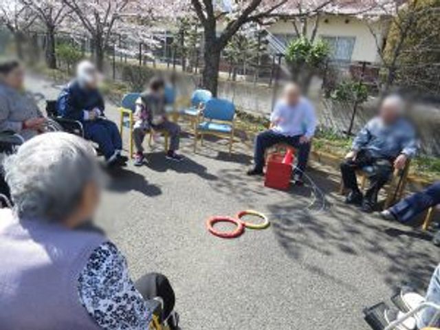屋外でのレクリエーション 庭 桜の木の下で、椅子に座って輪投げを楽しむ和やかなひとときです。交流が深まります。