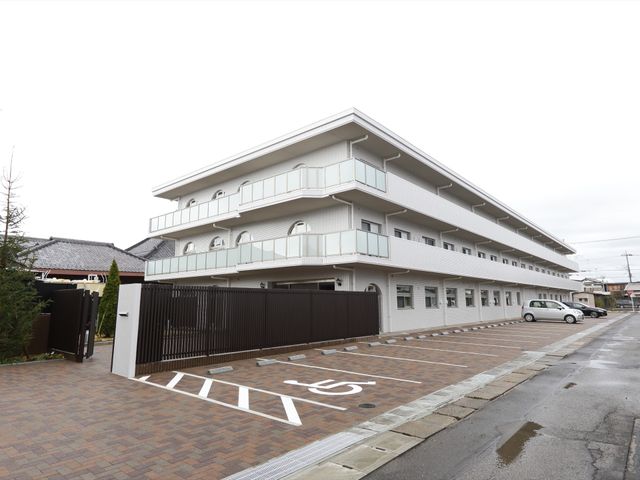 白い建物の外観 外観 広々とした駐車スペースが整備された白亜の建物です。バリアフリー設計のアプローチにより、どなたでも安心して出入りできる環境が整っています。