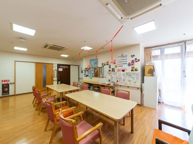明るい食堂の室内 食堂   大きな窓から光が入る、明るい食堂です。テーブル席がゆったり配置され、掲示物もあり、落ち着いて過ごしやすい雰囲気です。