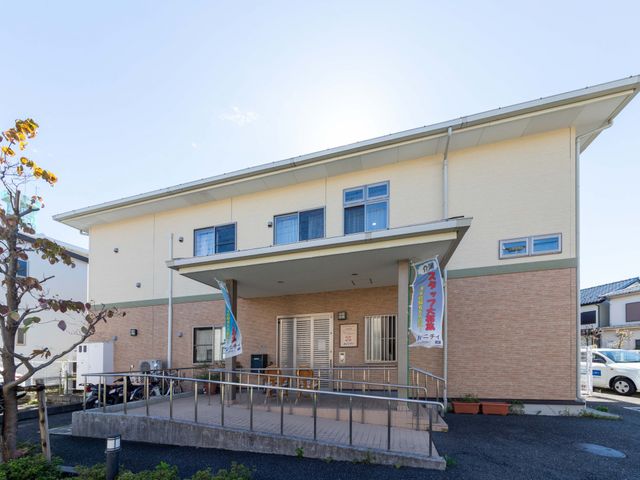 明るい外観の建物 外観   落ち着いた色合いの2階建てで、正面に屋根付きの出入口があります。段差の少ないアプローチがあり、出入りしやすそうです。