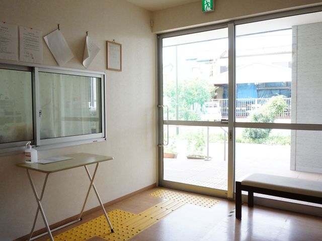 入口の明るい休憩コーナー 玄関 ゆったりとしたベンチが置かれた開放的なエントランスで、訪れる方々を暖かく迎えます。明るく落ち着いた雰囲気が漂っています。