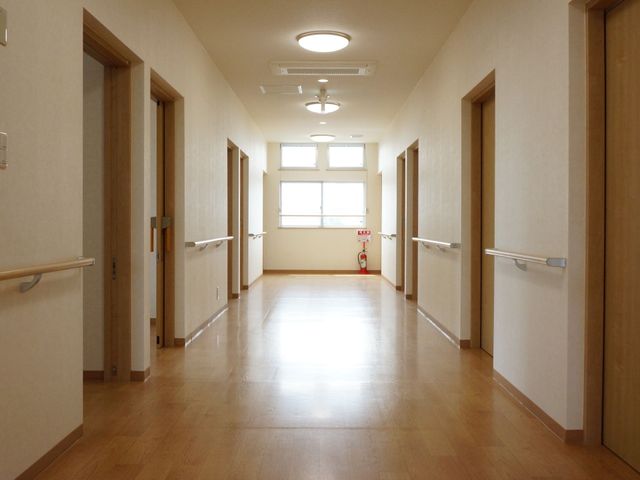 木目調の明るい廊下 通路 床から天井まで木目の温もりを感じさせ、ゆったりとした空間の廊下。手すりが設置されており、安全に配慮された設計です。