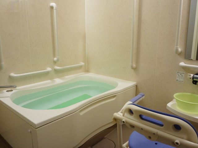 手すり付き浴槽設備 浴室 手すりや椅子が設置され、安全に配慮された清潔な入浴スペースです。利用者の快適さを追求した環境を提供しています。