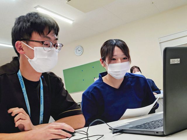 スタッフがPC作業する多目的室 多目的室   マスク姿のスタッフが、パソコンを使いながら確認作業をしています。明るい室内で、複数人が連携しやすい雰囲気です。