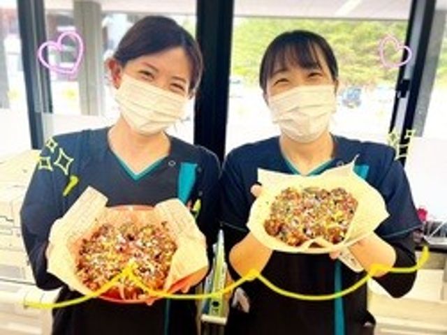 マスク姿のスタッフ2人が料理を持つ食堂 食堂   マスクを着けたスタッフの方が2人並び、料理を手にしています。窓際の明るい食堂で、働く様子が伝わります。