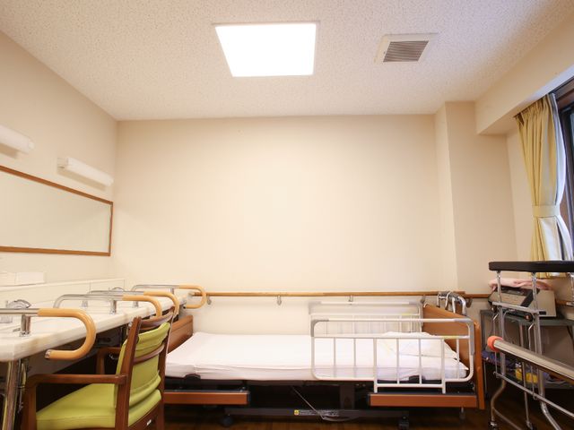 居室のベッドと椅子 部屋 ゆとりあるスペースの個室で、リラックスしてお過ごしいただけます。機能的なベッドと椅子が配置されており、快適な生活環境を整えています。