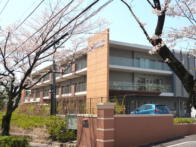 桜並木のある施設外観 桜が咲く温かな雰囲気の入り口付近です。周辺環境も穏やかで、安らぎを感じさせる場所となっています。