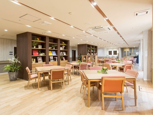 快適なダイニングエリア レストラン・ラウンジ 明るく広々としたダイニングで、利用者様は食事やコミュニケーションを楽しまれています。木目調の家具が暖かい雰囲気を醸し出し、心地よい空間が広がっています。