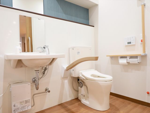 清潔な洗面台とトイレ トイレ 手すりが付いた清潔で安全なトイレです。利用者の方々が快適にお使いいただける環境が整っています。