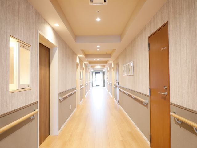 清潔感ある廊下 廊下 木目調のフロアが温かみを感じさせ、手すりが設置された明るい通路です。廊下は広々としており、ゆったりと歩ける造りになっています。