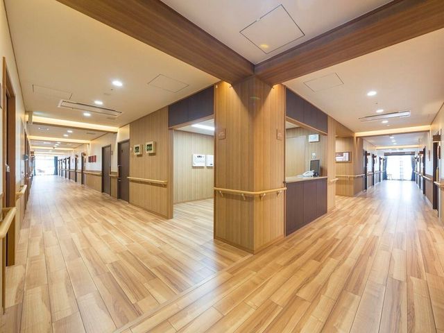 明るく広々とした廊下 廊下 木目調の壁と床が温もりを感じさせる廊下です。手すりが設置されており、歩行時の安全を支えます。