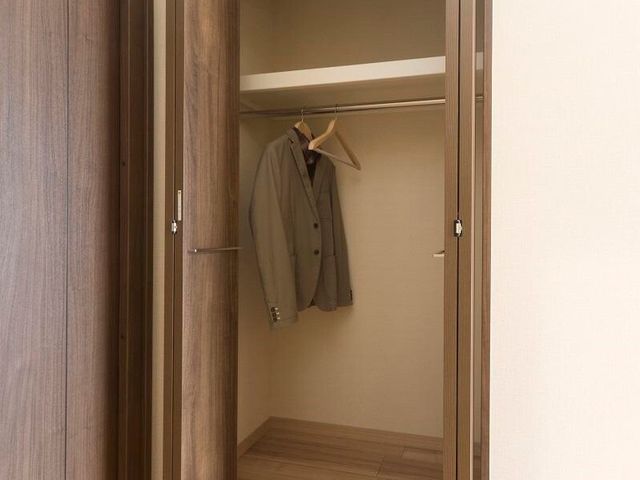 茶色の洋室クローゼット 収納 木目調のクローゼットは、洋室に調和した落ち着きあるデザインです。衣類の整理に便利な広々とした収納スペースを備えています。
