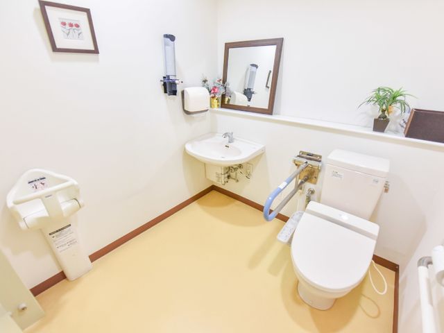 バリアフリー対応の浴室 トイレ 手すり付きの清潔なトイレです。安全面を考慮した設計になっており、安心してご利用いただける設備です。