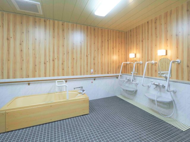 木目調の浴室設備 浴室 ゆとりを持った木目調のバリアフリー設計の浴室です。手すりや座浴椅子も備え、安全に配慮されています。