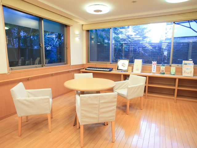 和やかな中庭付き休憩室 内装 木の温もりあふれる明るい休憩スペースです。大きな窓からは中庭の緑が見え、ゆったりと寛げる環境が整っています。