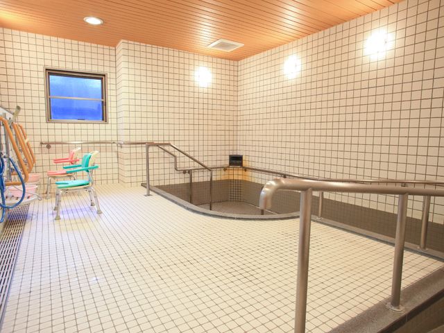 快適な施設の浴室 大浴場 ゆったりとした浴槽と手すりが備わった安全性を考えた浴室です。機能的なシャワーチェアも完備し、快適な入浴を支援します。