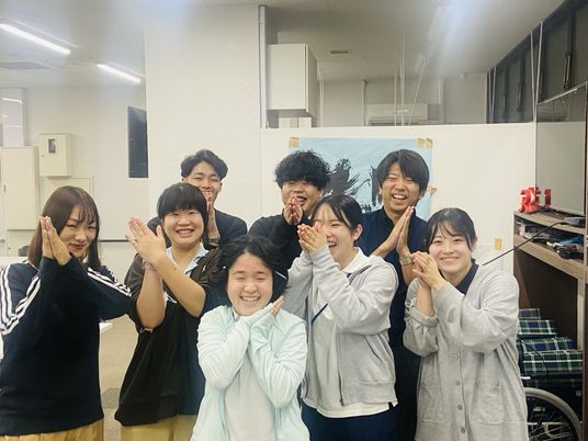 笑顔のスタッフが並ぶ室内  