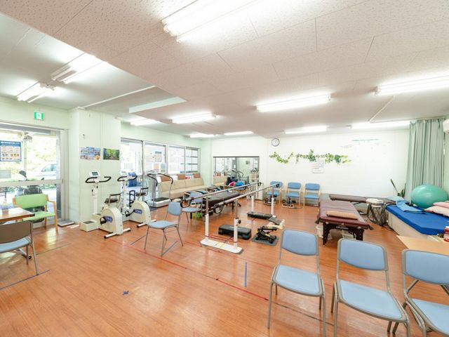 機能訓練室 機能訓練室 明るく広々とした空間では、さまざまなリハビリ器具を利用しながら体を動かせます。緑のデコレーションが雰囲気を和らげています。