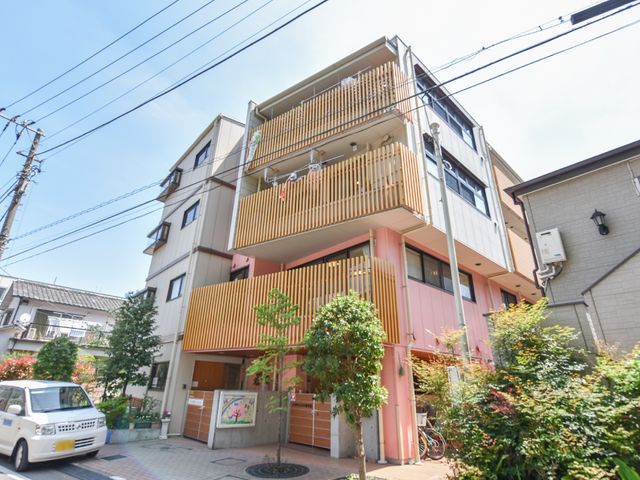 オレンジ色の外観 外観 落ち着いたオレンジ色の建物には緑が映え、温かみのある外観が迎えてくれます。花々が彩りを添えるエントランスは、明るい雰囲気を演出しています。