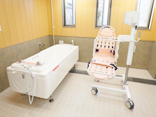 施設の写真 広々とした空間が確保された機械浴室である。左端に大きな浴槽があり、その横に浴室用のストレッチャー昇降装置がある。