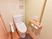 明るい色合いのフローリングにレグホーン色の壁の、あたたかみのある、落ち着いた雰囲気のトイレの個室である。