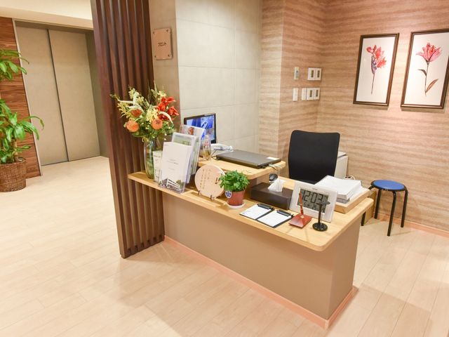 エントランスの受付カウンター 受付 落ち着いた色合いのフロントは清潔感があり、来訪者を温かく迎えます。機能的なデザインで働きやすい環境が整っています。