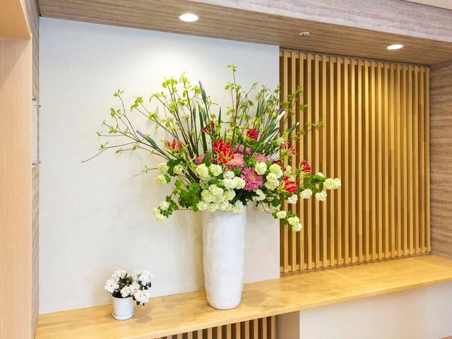 エレガントな壁飾り 玄関 暖かみのある木製パネルと洗練された花瓶が印象的なエントランスです。訪れる方々を優しい雰囲気で迎えてくれます。
