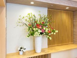 白い花瓶の生花と木目調壁