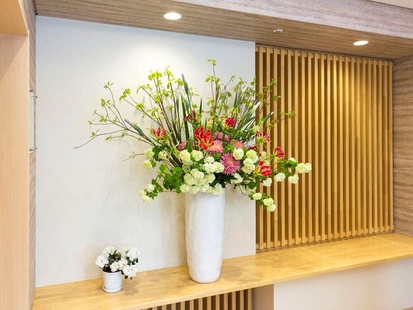 白い花瓶の生花と木目調壁