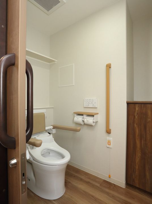 トイレに設置された木製グリップの下には、非常時にスタッフを呼び出すことができるブザーが取りつけられている。