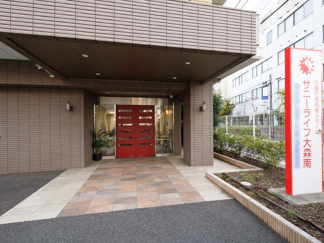 施設のエントランス風景 玄関 赤いゲートが目印の落ち着いた色合いのエントランスです。訪れる人々を暖かく迎え入れるような設計になっております。